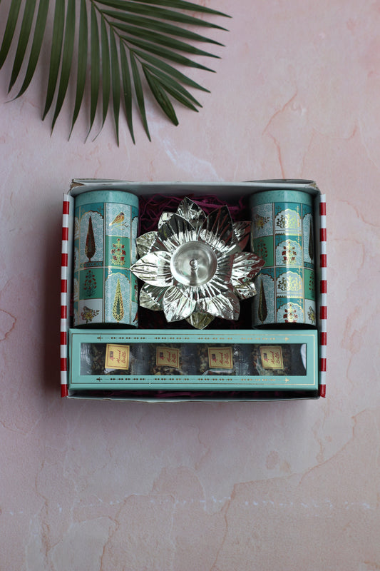 Decorative box with a crystal dish and green packaging on a light pink surface with a leaf.