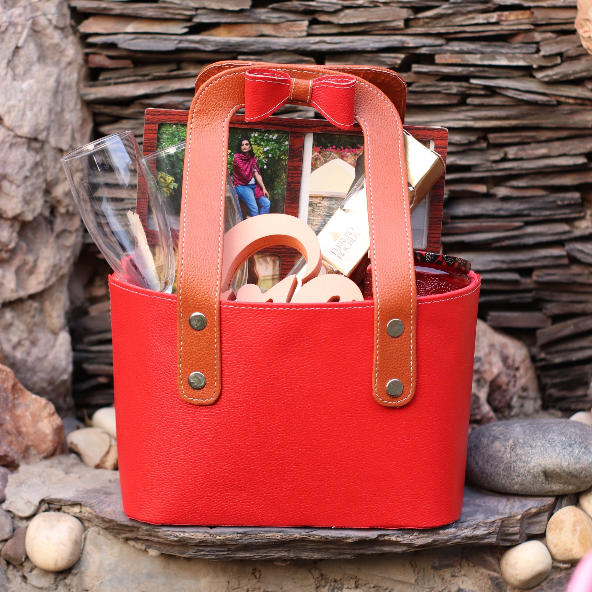 A red brown leather feel basket with a handle, metal buckle, and a bow,